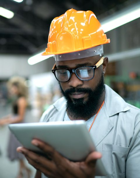 man wearing hard hat looking at tablet