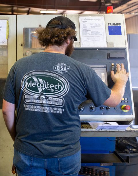 metaltech workers operates a metal cutting machine