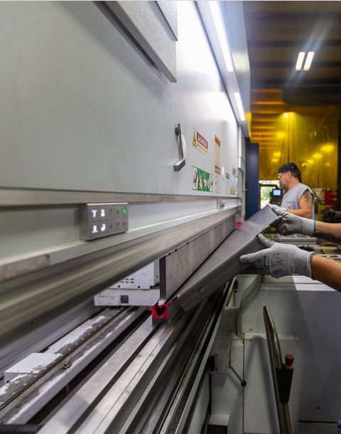 man wearing gloves operating metal forming machine