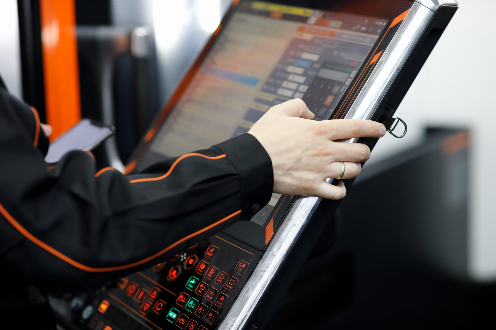 Operator of CNC machining center working with touch screen control panel.