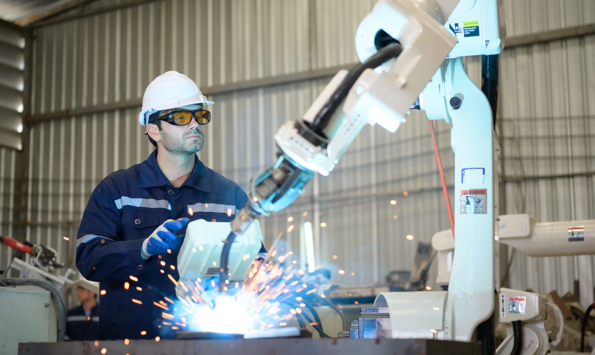Young male engineers are manipulating a welding robot hand. By combining welding manipulation with a control panel for precise welding control. Rapid and very secure